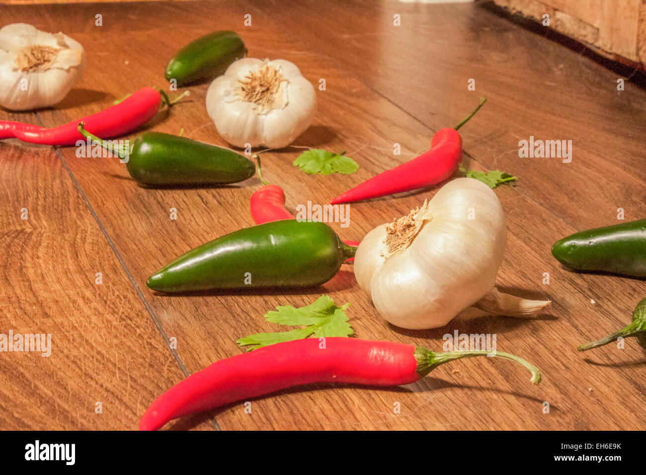 Garlic between jalapenos and chili peppers, on wooden ground Stock Photo