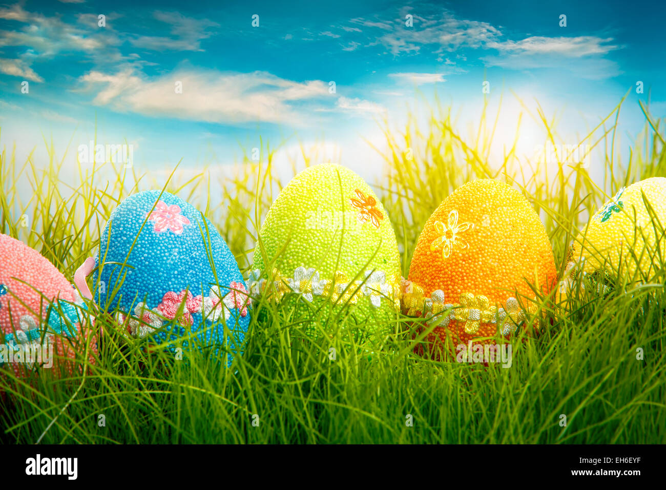 Decorated easter eggs in the grass on blue sky background Stock Photo ...