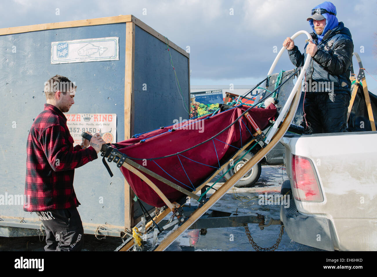 Jason Mackey (right) loads a dog sled in the back of a truck following the Ceremonial Start of the 2015 Iditarod Dog Sled Race at Anchorage (USA) on March 7, 2015. The race will resume with the official start in Fairbanks on March 9. Photo: Joshua Corbett/dpa (zu dpa: Alaska, Land des Hechelns: «Das härteste Schlittenrennen der Welt» vom 08.03.2015) Stock Photo
