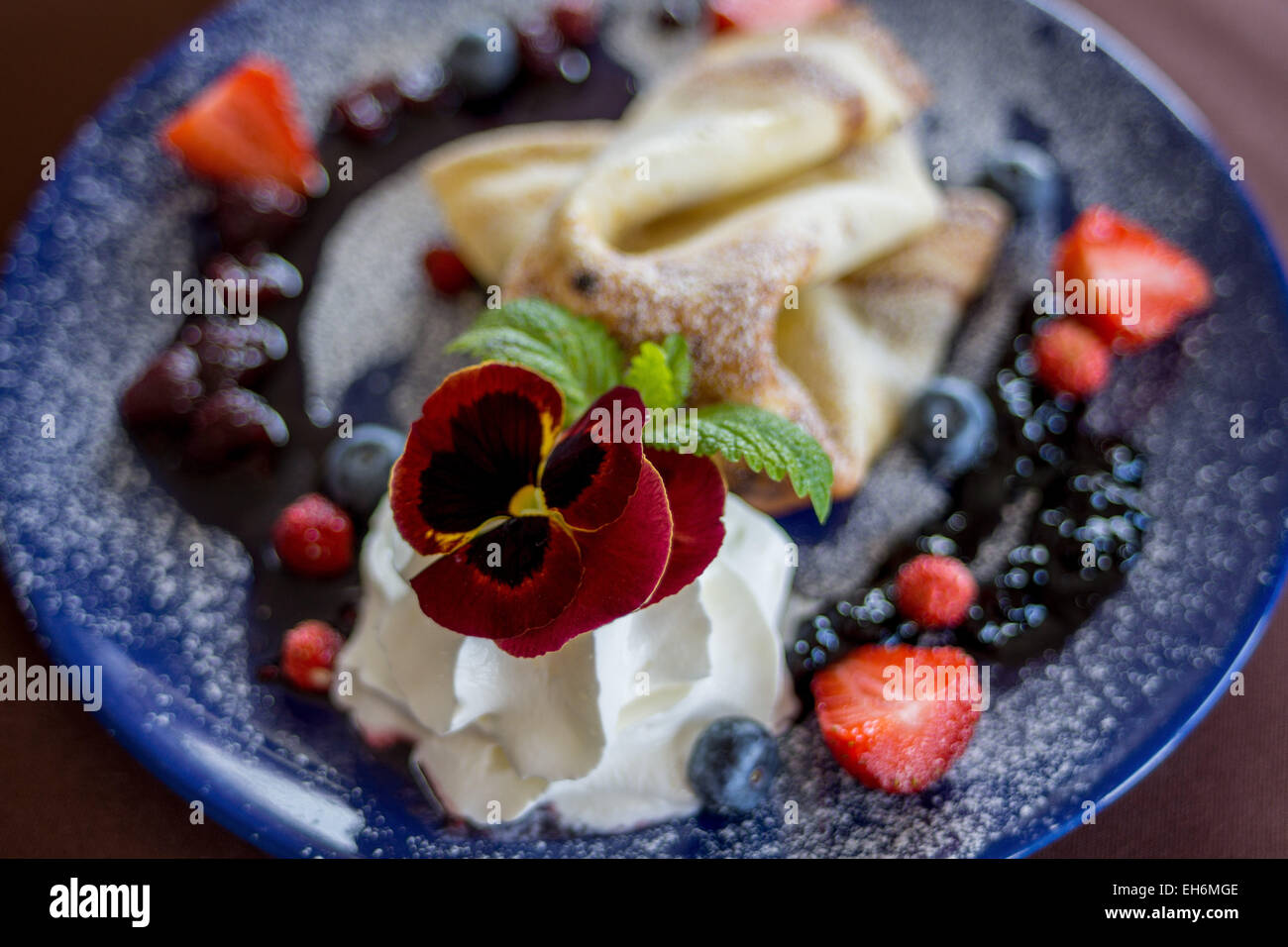 Desert  pancake with sweet cheese , whipped cream, blueberries,strawberries decorated with Pansy Stock Photo