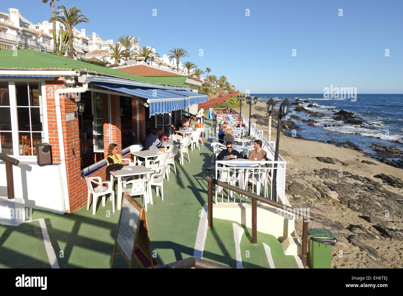 Tourists in winter season at beach bar, cafe, restaurant at coast Southern Spain, La Cala, Andalusia. Spain. Stock Photo