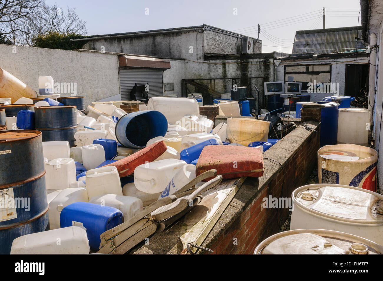 Lots of plastic and metal containers, containing chemicals such as surfactants, phosphates, illegally dumped by immigrants running an illegal car wash Stock Photo