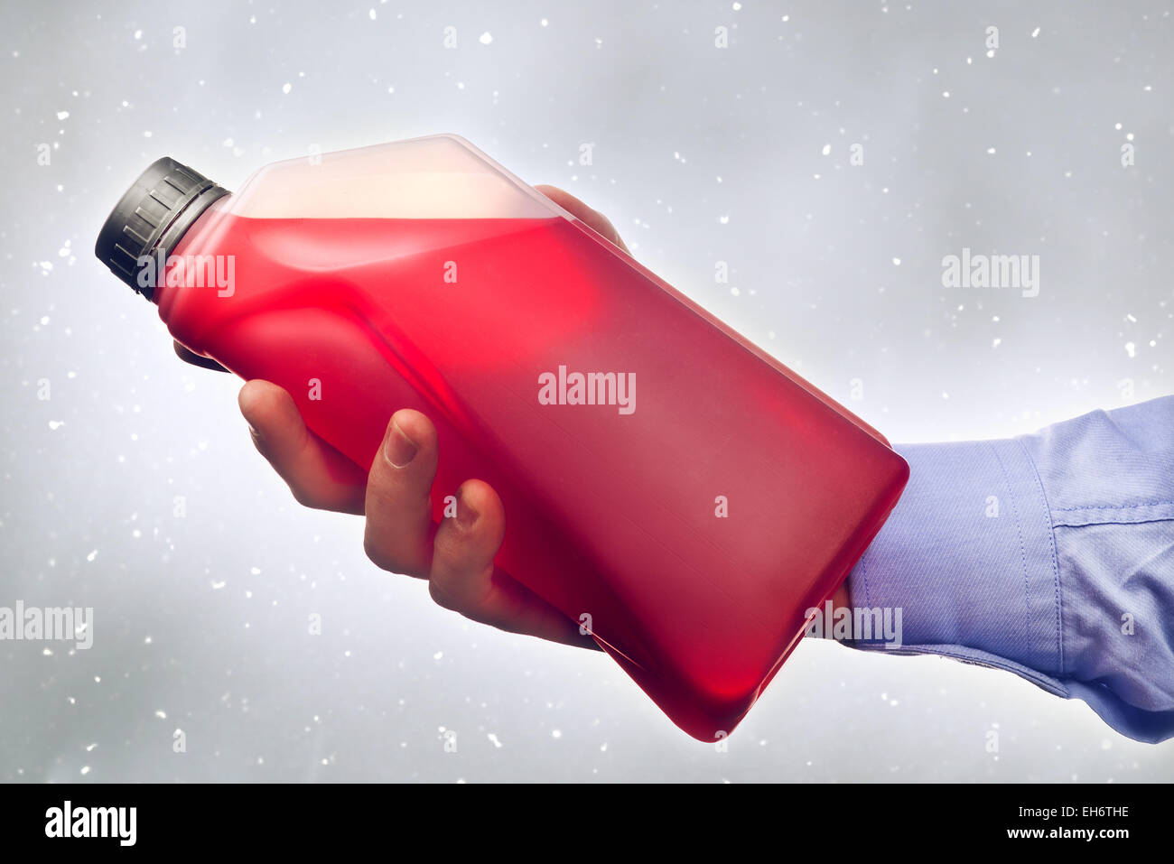 Male hand holding a bottle of antifreeze additive water-based liquid for winter condition driving. Toned image. Stock Photo