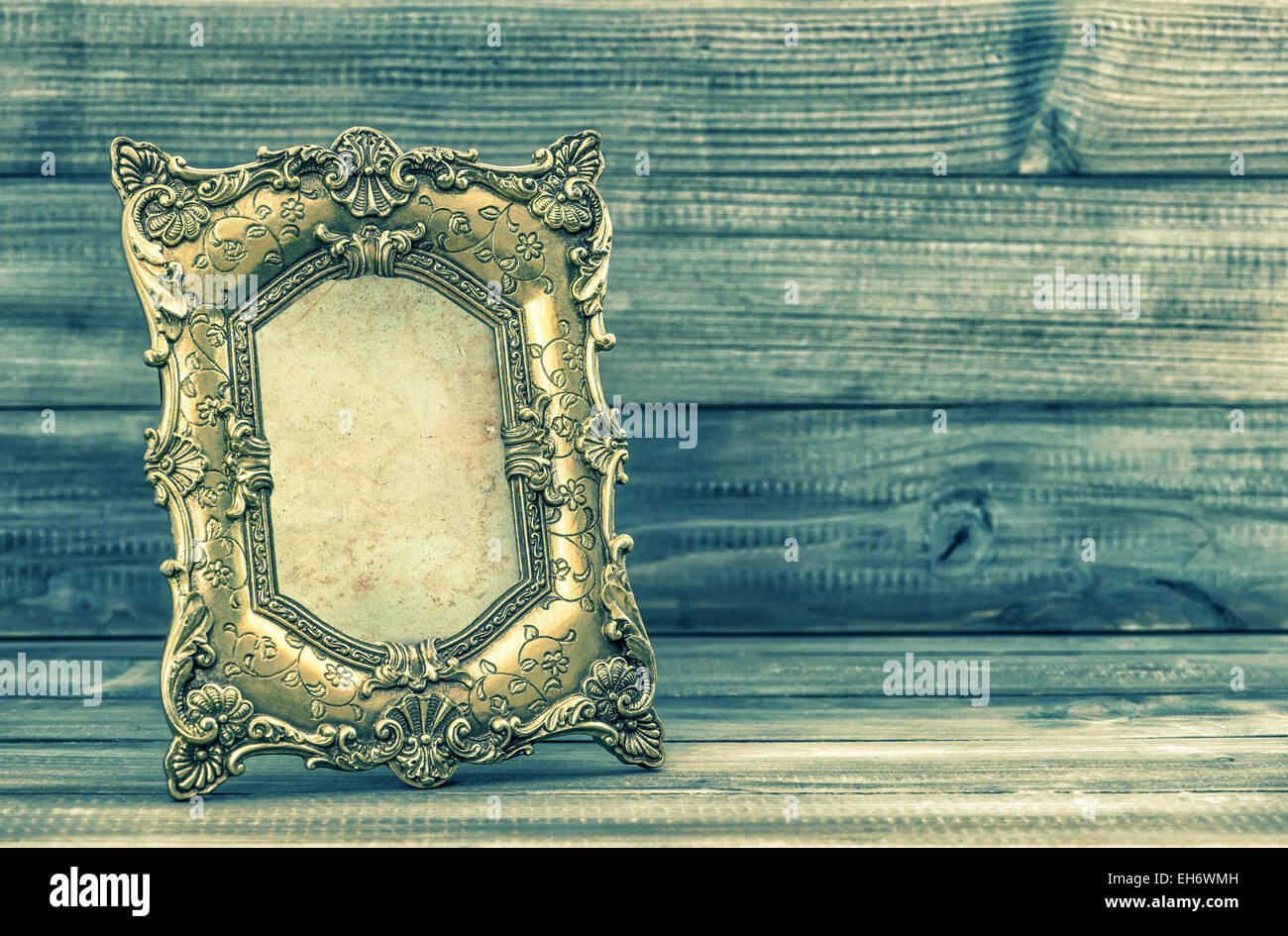 Golden baroque picture frame on wooden background. Retro style toned