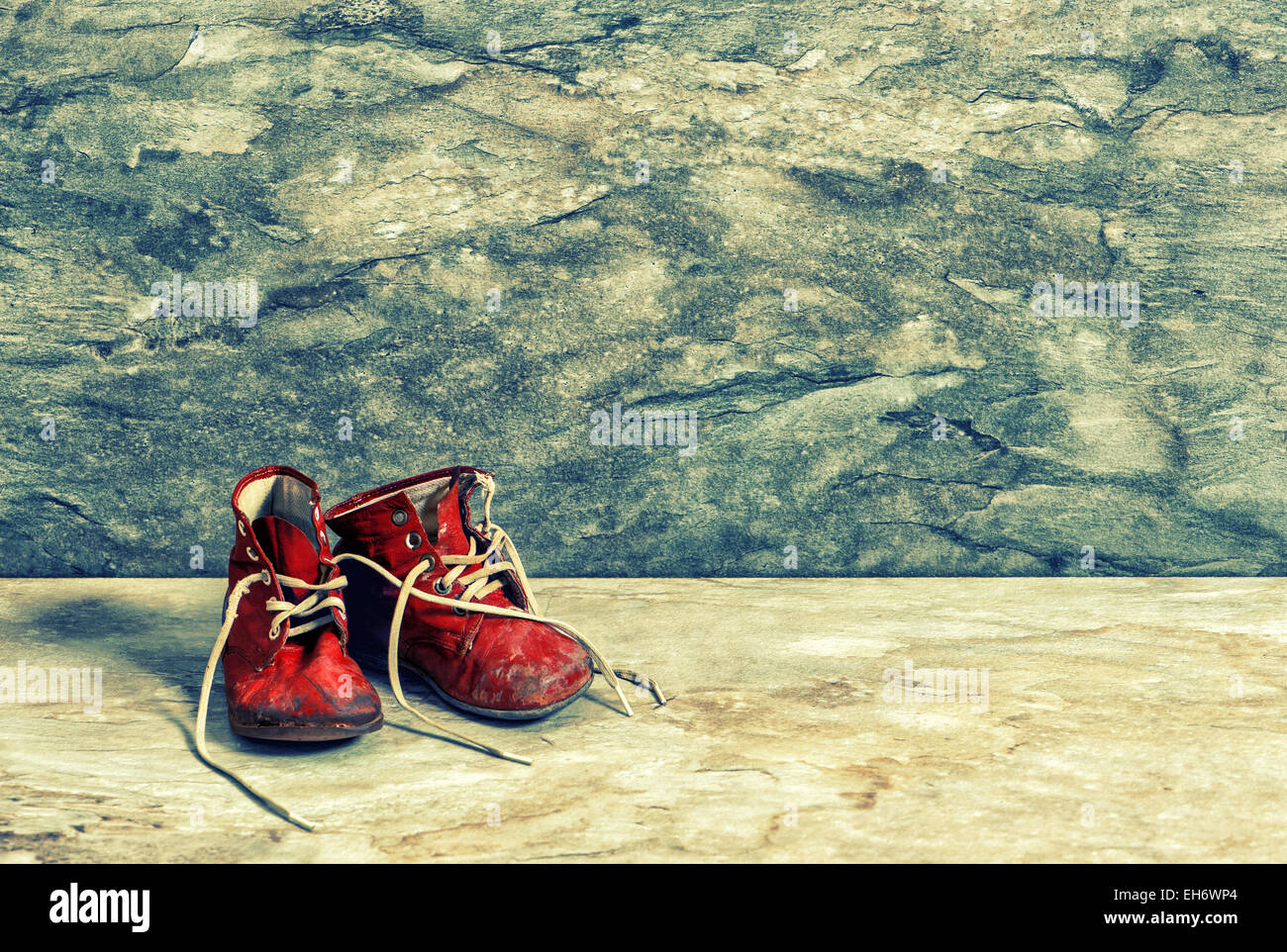 Antique red baby shoes on rustic background. Vintage Instagram style toned picture Stock Photo