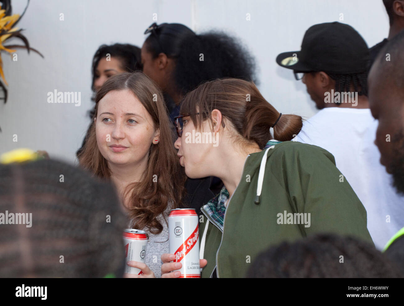 At the Hackney carnival two white young women drinking appropriately Jamaican Red Stripe beer. Stock Photo
