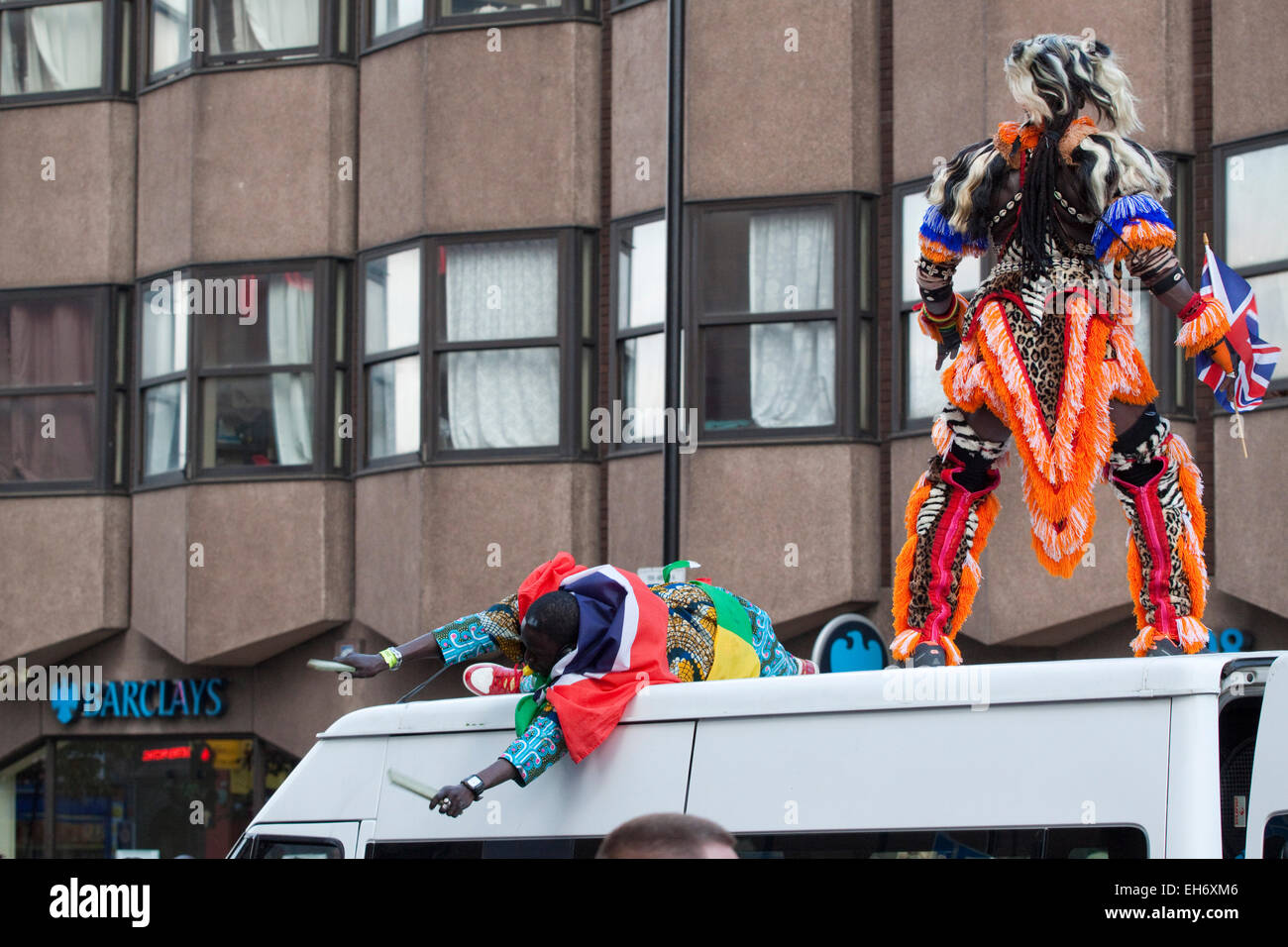 Two spectacularly dressed carnival makers on top of a white van Stock Photo