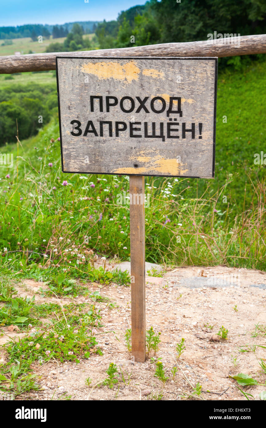 Old wooden sign with Russian text label means passage is not allowed stands on the edge of the ravine Stock Photo