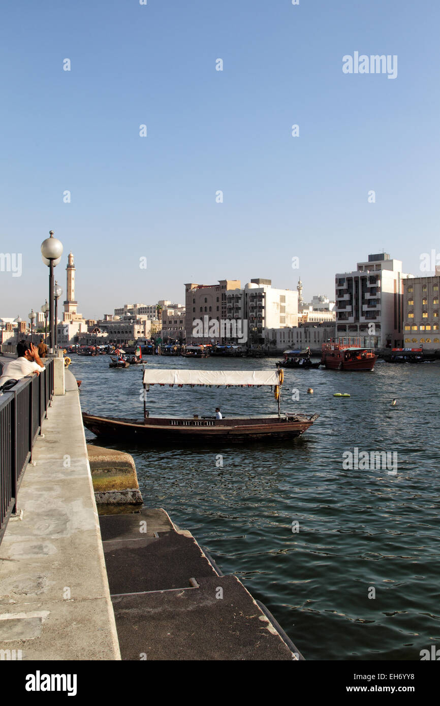 View over Dubai Creek from Deira to Bur Dubai. Abras, typical ferry boats in Dubai, are crossing the river; the minaret of the G Stock Photo