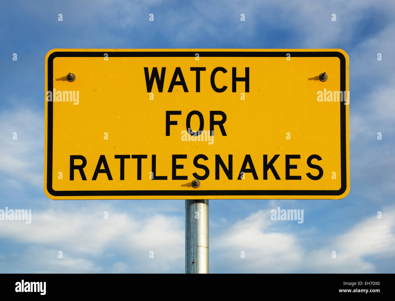 watch for rattlesnakes sign with partly cloudy blue sky background Stock Photo