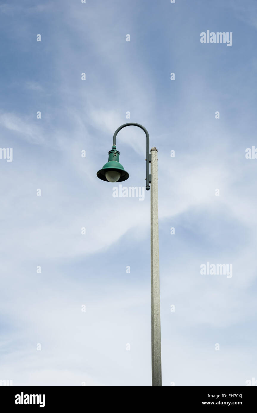 green bent down streetlamp with partly cloudy sky background Stock Photo