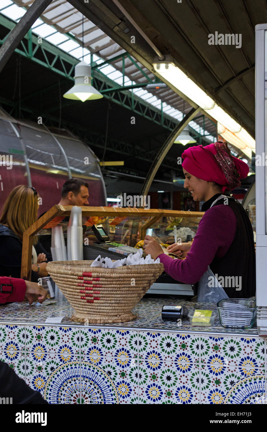 A woman operates the cash register at a Moroccan restaurant in the Marché des Enfants Rouges, an organic marketplace in Paris. Stock Photo