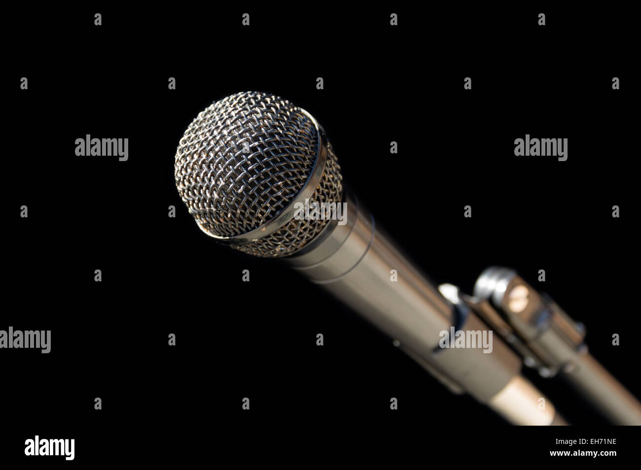 silver gray microphone on a stand with a black background Stock Photo