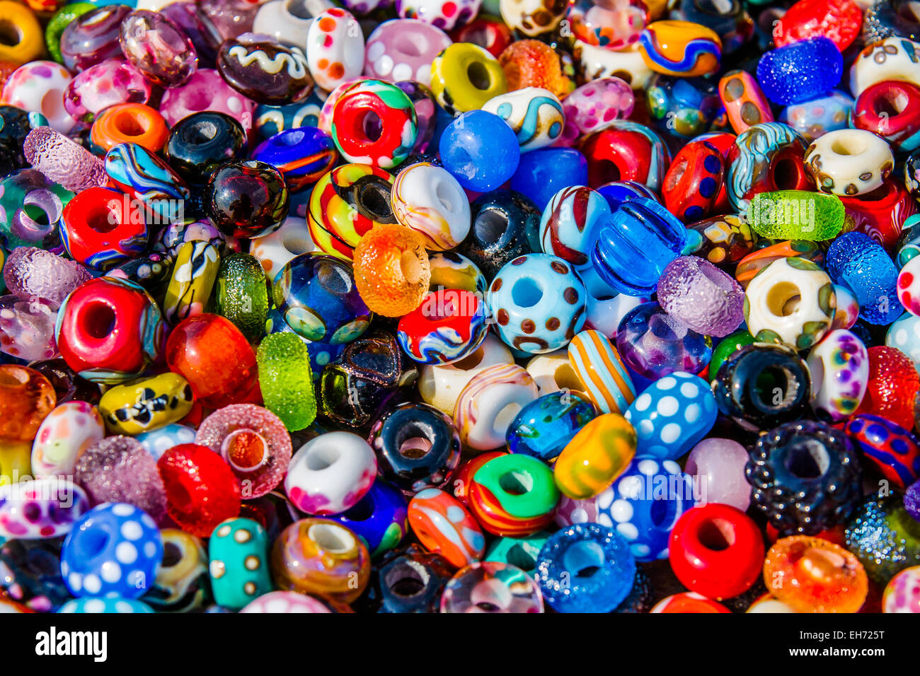 Glass and clay beads of different shapes and colors displayed in bulk at local fair Stock Photo