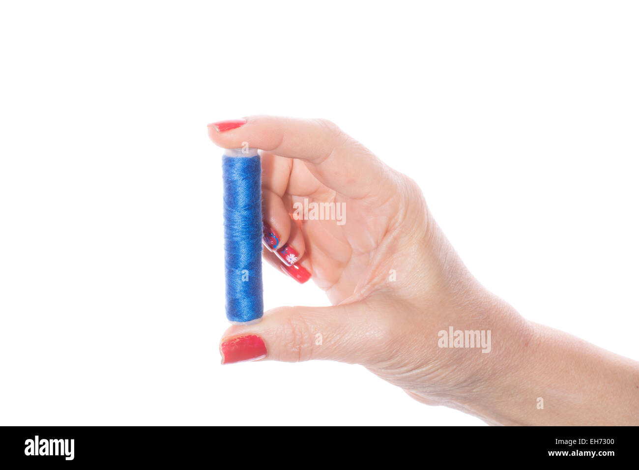 Female hand holding blue sewing thread on a white background Stock Photo