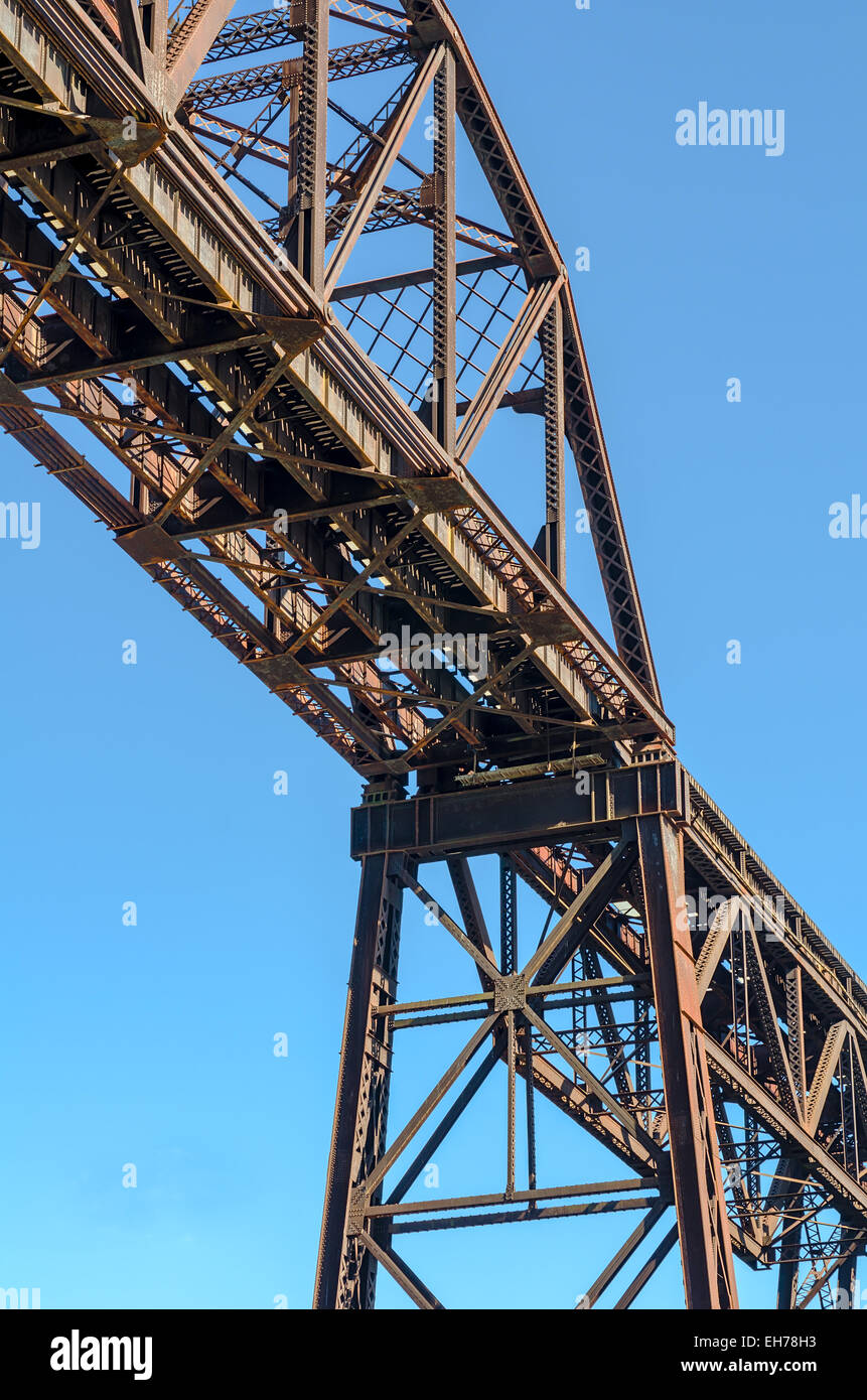 Section of Rusty Steel Girder Railroad Bridge in Bright Daylight with Clear Blue Sky Background. Stock Photo