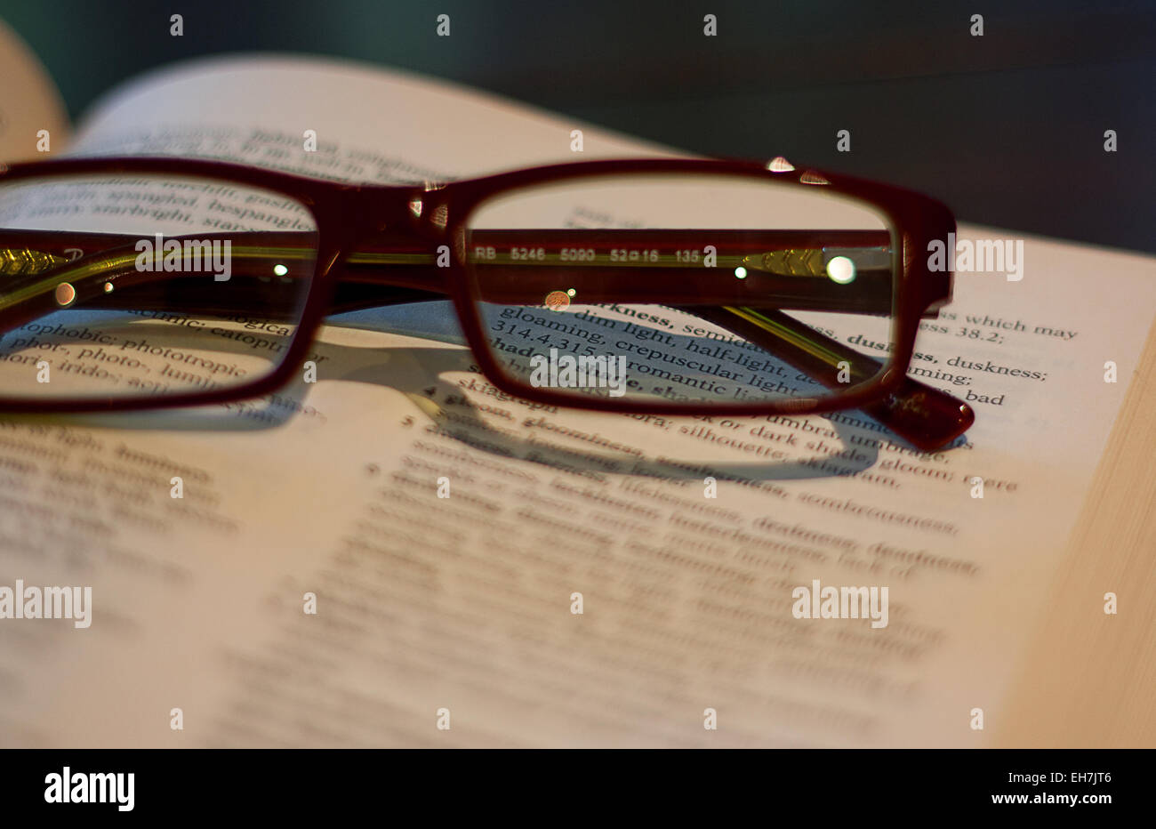 Reading glasses on a thesaurus focused on the words through the lens. Stock Photo