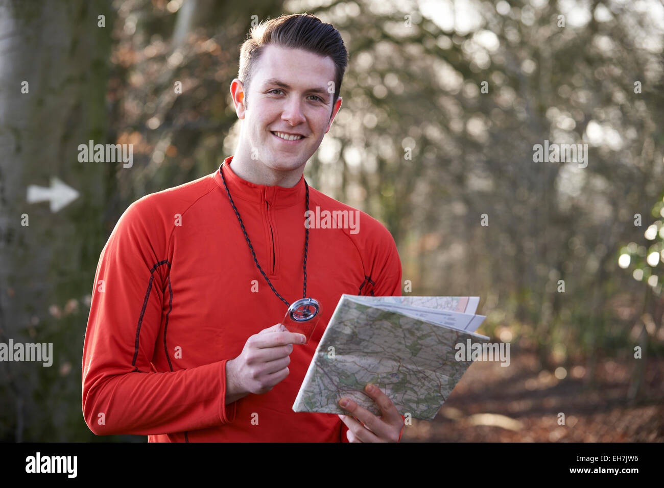 Man Orienteering In Woodlands With Map And Compass Stock Photo