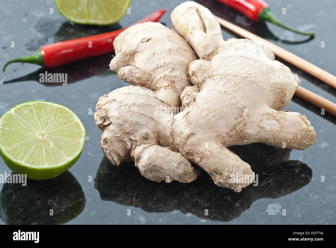 Fresh ginger together with lime, red chili and chopsticks. Stock Photo