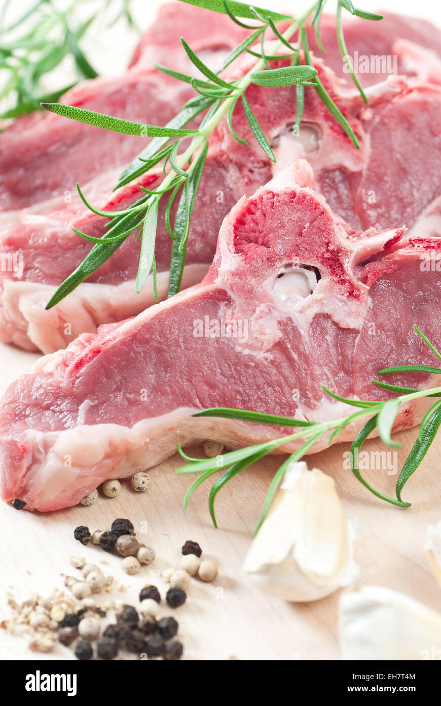 Raw lamb chops with fresh rosemary, garlic and pepper. Stock Photo