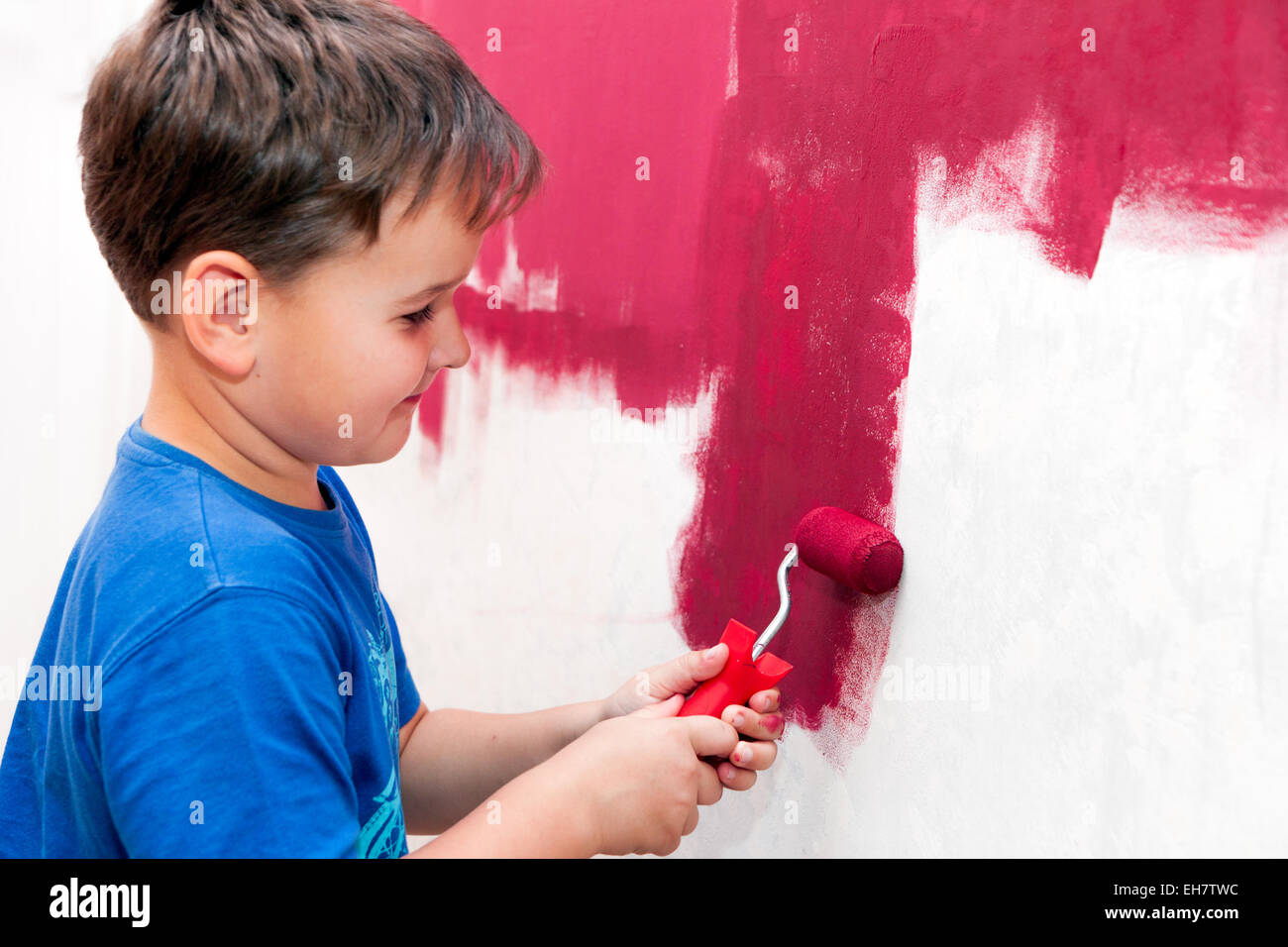boy painting the wall red in the apartment Stock Photo