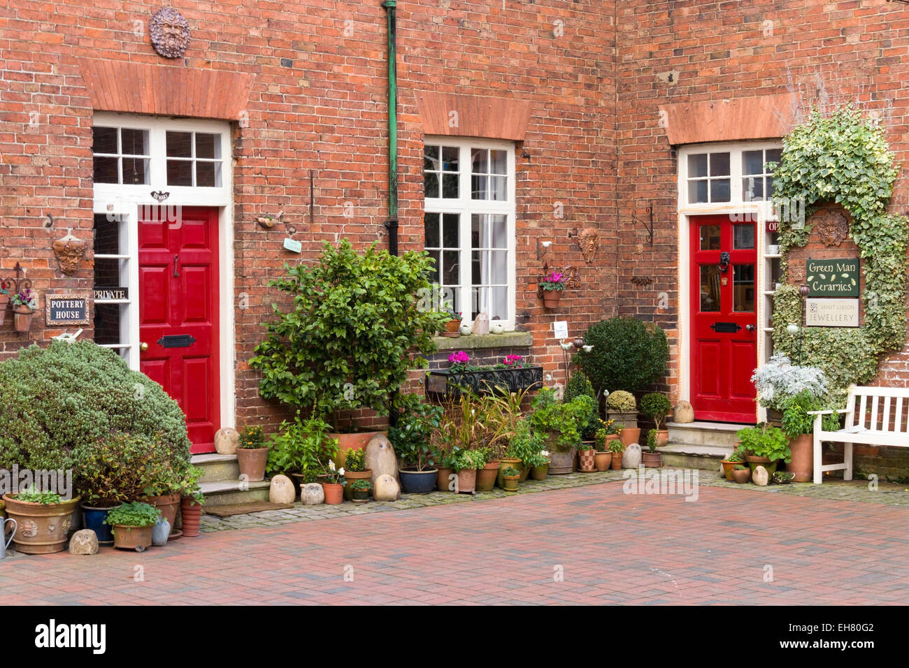 Red brick cottages with red front doors Ferrers Art and Craft Centre, Staunton Harold, Ashby de la Zouch, England, UK. Stock Photo