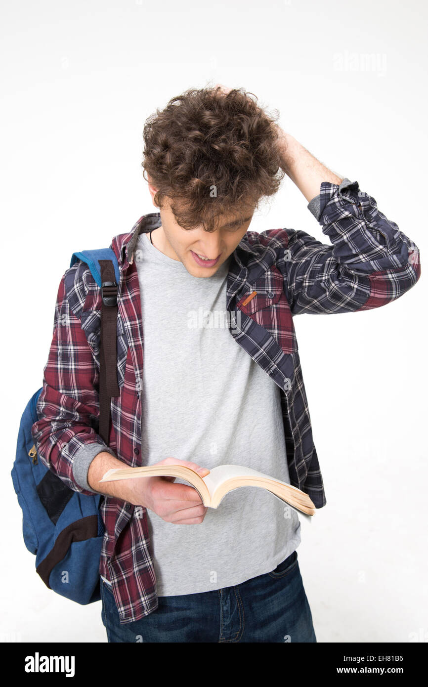 Portrait of a young male student reading book over gray background ...