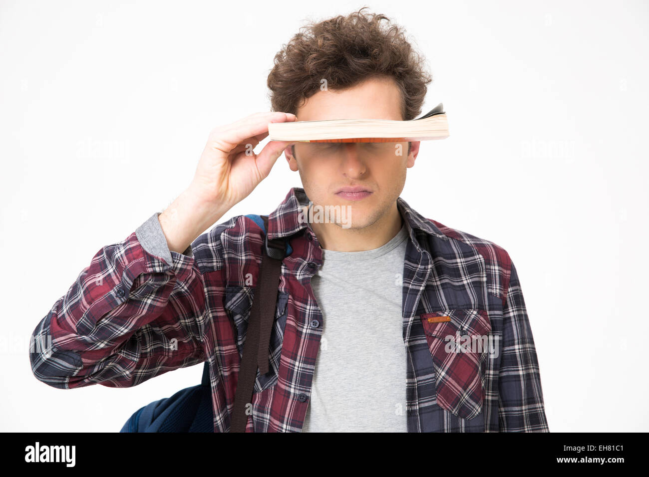 Young man covering his eyes with book over gray background Stock Photo ...