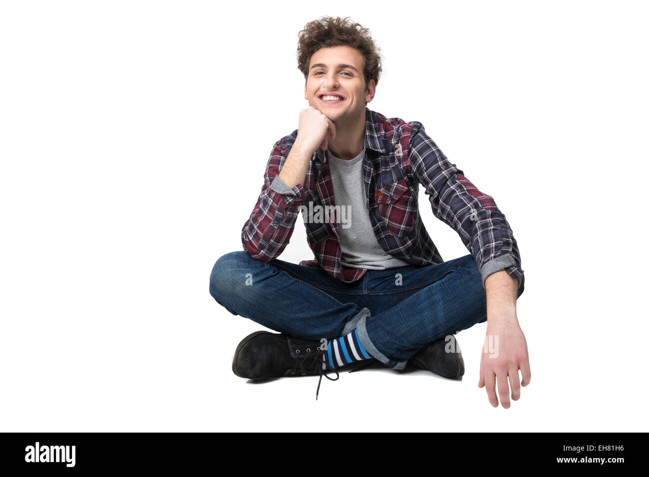 Smiling young man sitting on the floor over white background Stock ...