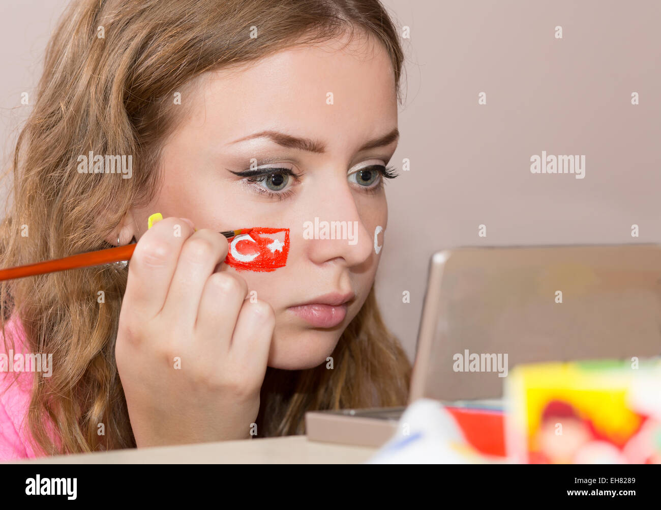 Young female making up her face with Turkish flag Stock Photo