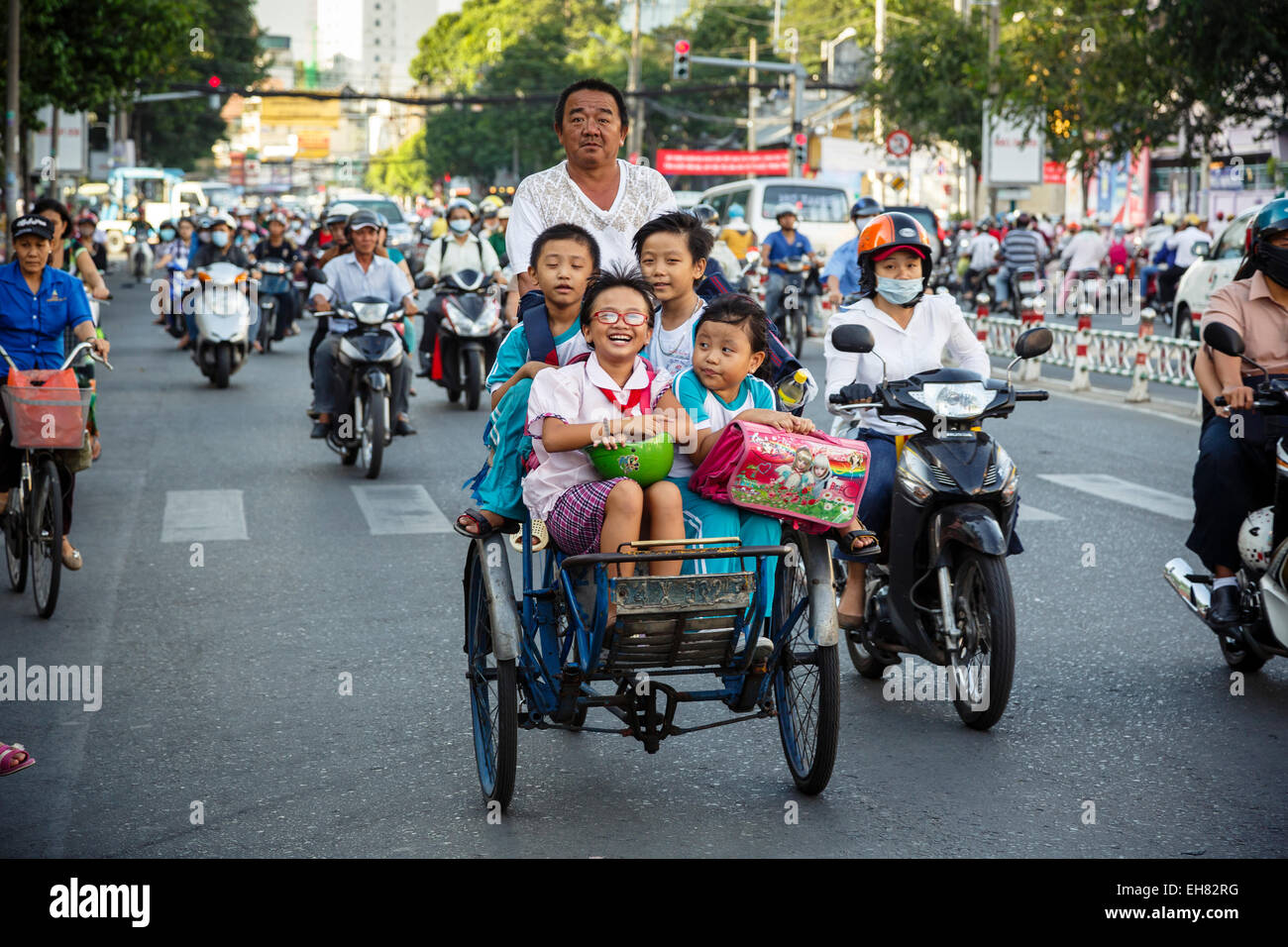 School kids riding a cyclo on a busy street, Ho Chi Minh City (Saigon), Vietnam, Indochina, Southeast Asia, Asia Stock Photo