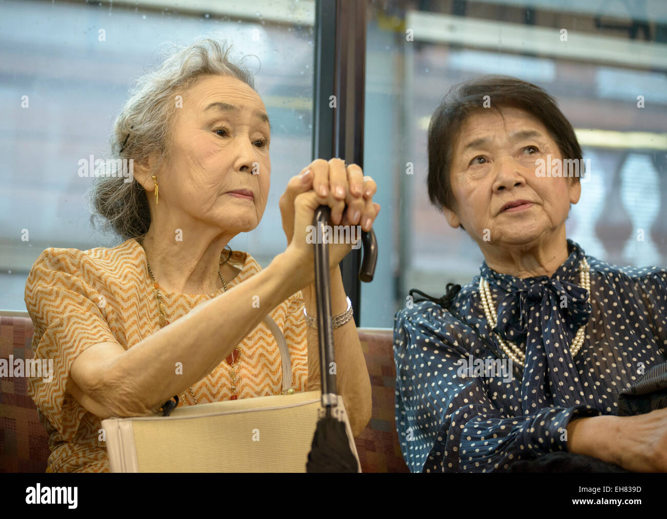 Two well-dressed elderly Japanese ladies on a train in Tokyo. Senior citizens in Japan; old Japanese people; elderly Asians; aging population Asia Stock Photo