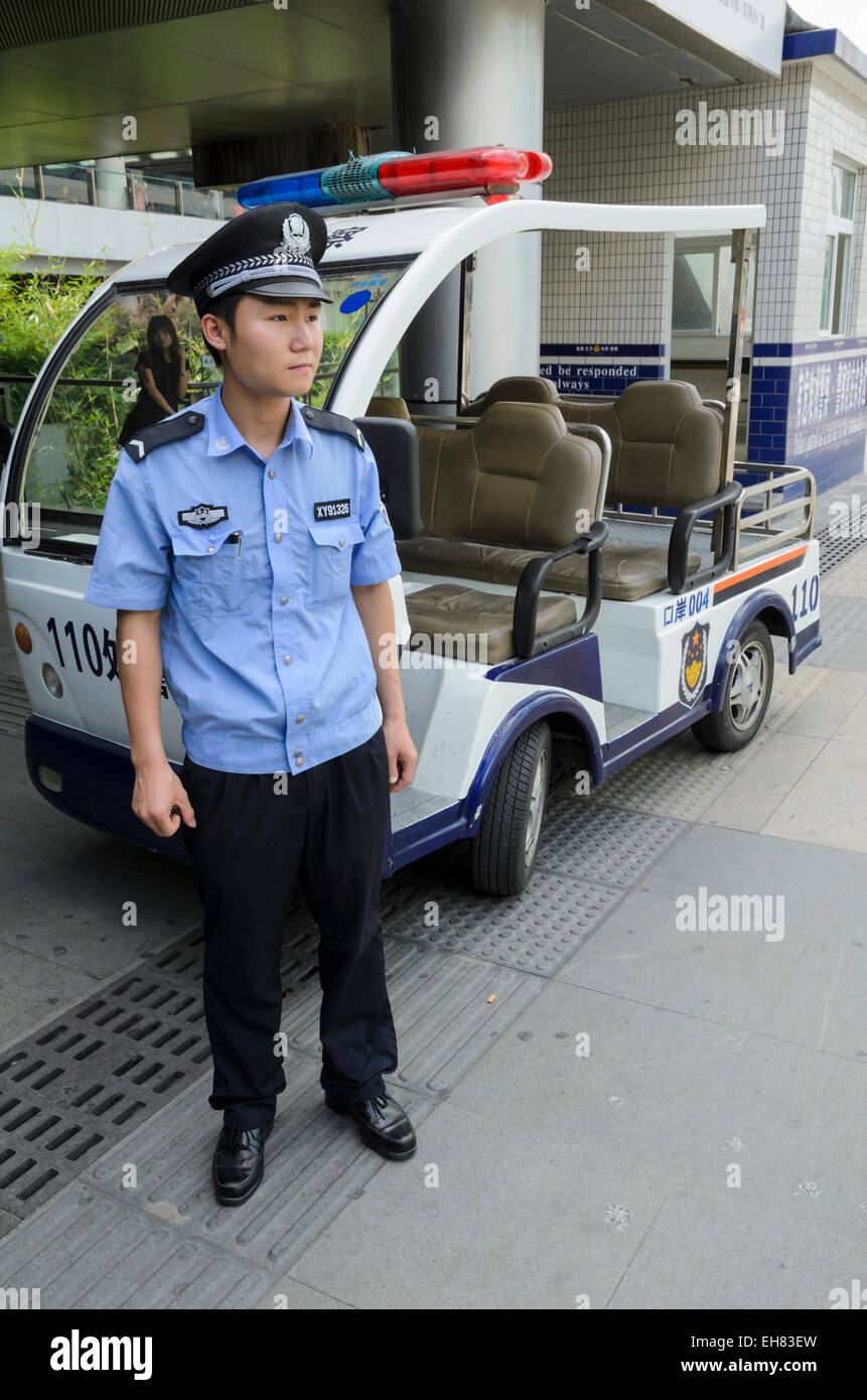 A Chinese policeman stands by his electric cart - common short-distance police transport in China Stock Photo