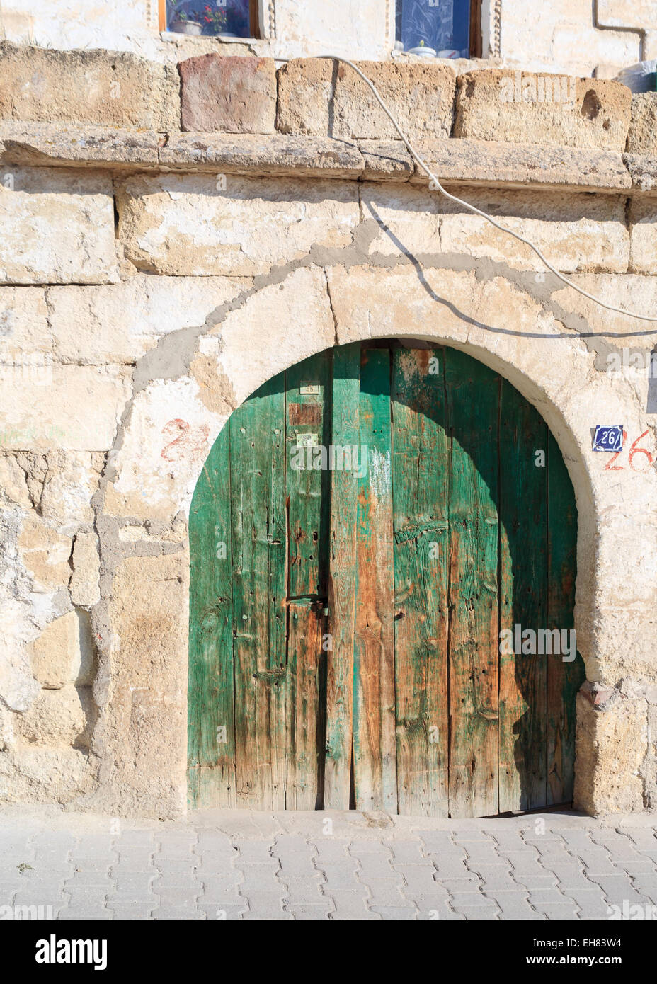Old, dilapidated green wooden door in a stone arch doorway in a wall, Goreme, Cappadocia, Turkey Stock Photo