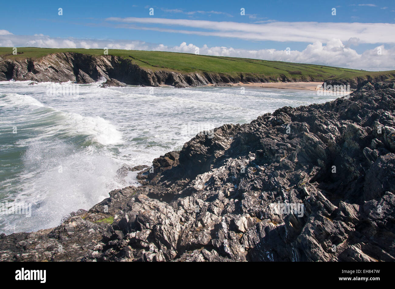 Waves crashing on the rocks at Porth Joke near Newquay in Cornwall on a sunny spring day. Stock Photo