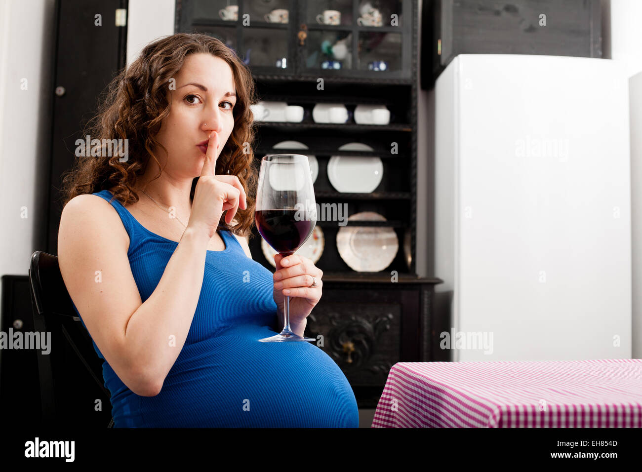 Woman in full term pregnancy drinking red wine. Stock Photo