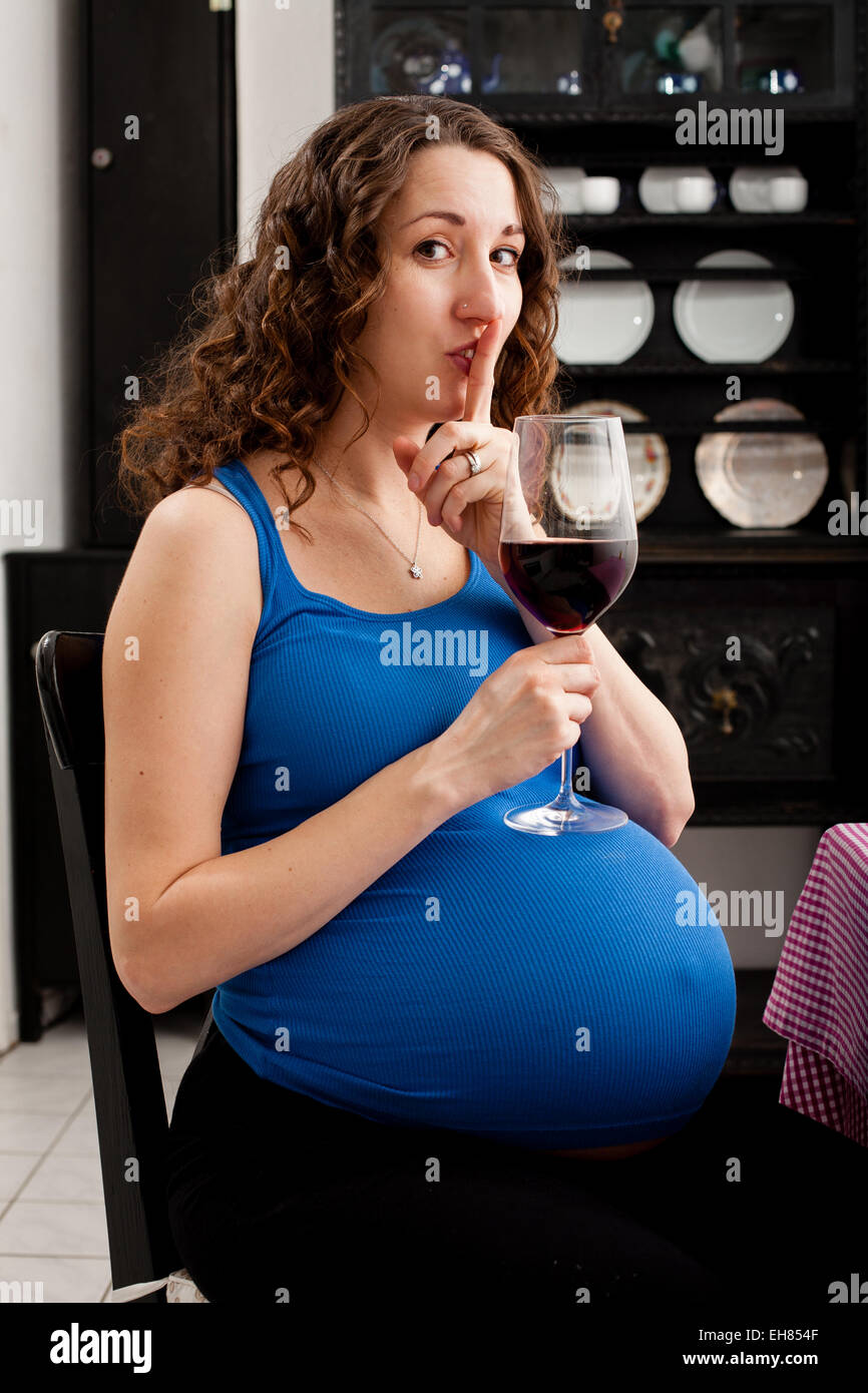 Woman in full term pregnancy drinking red wine. Stock Photo