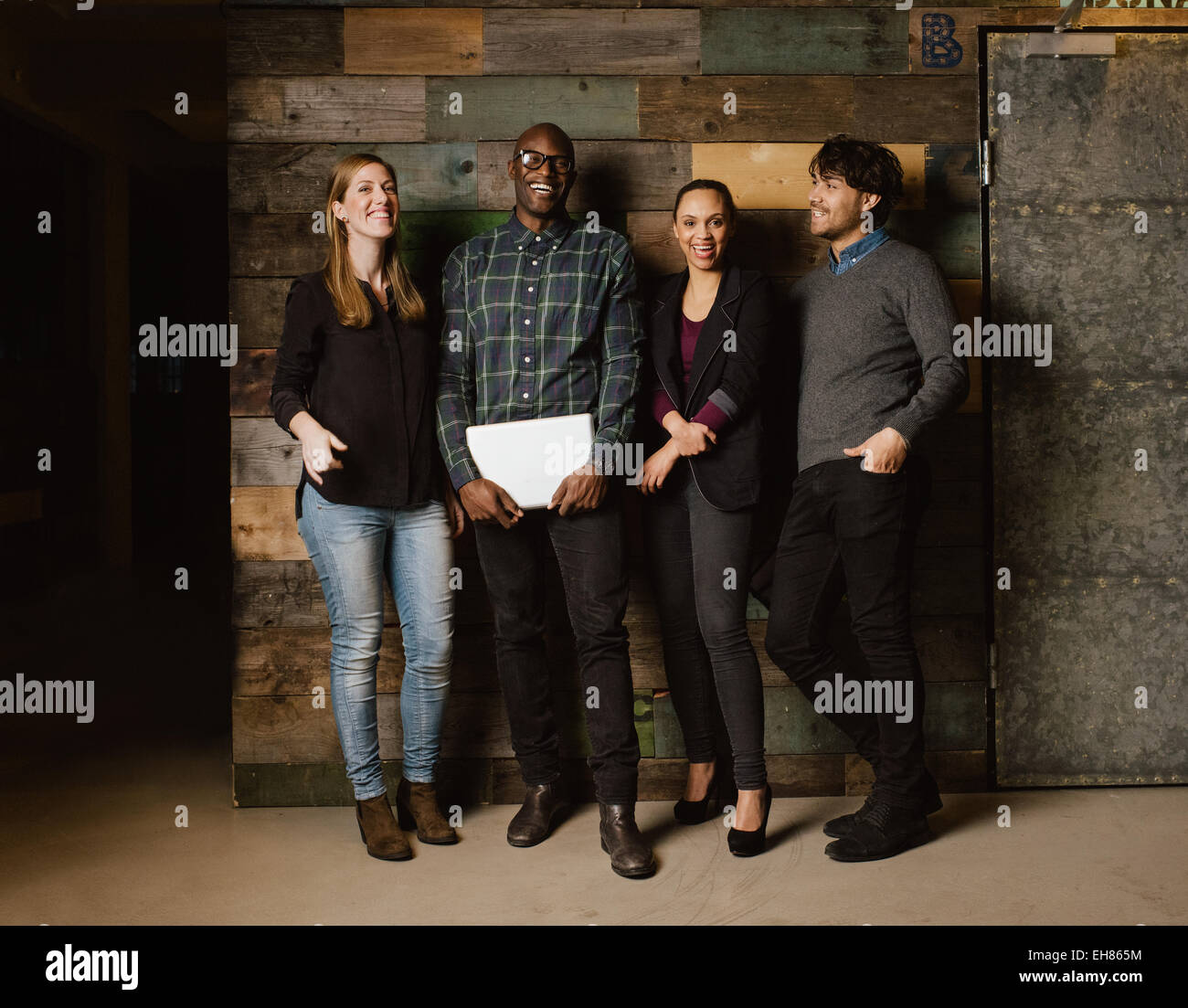 Portrait of young professionals laughing while standing together in office. Multi ethnic business team looking happy together. Stock Photo