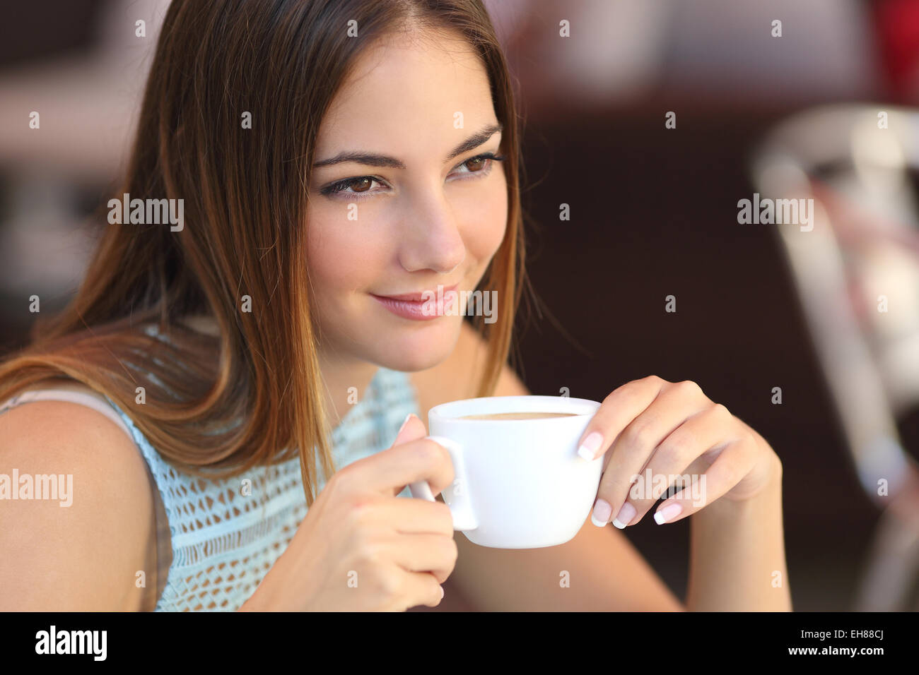 Candid woman thinking in a coffee shop holding a cup with an unfocused background Stock Photo