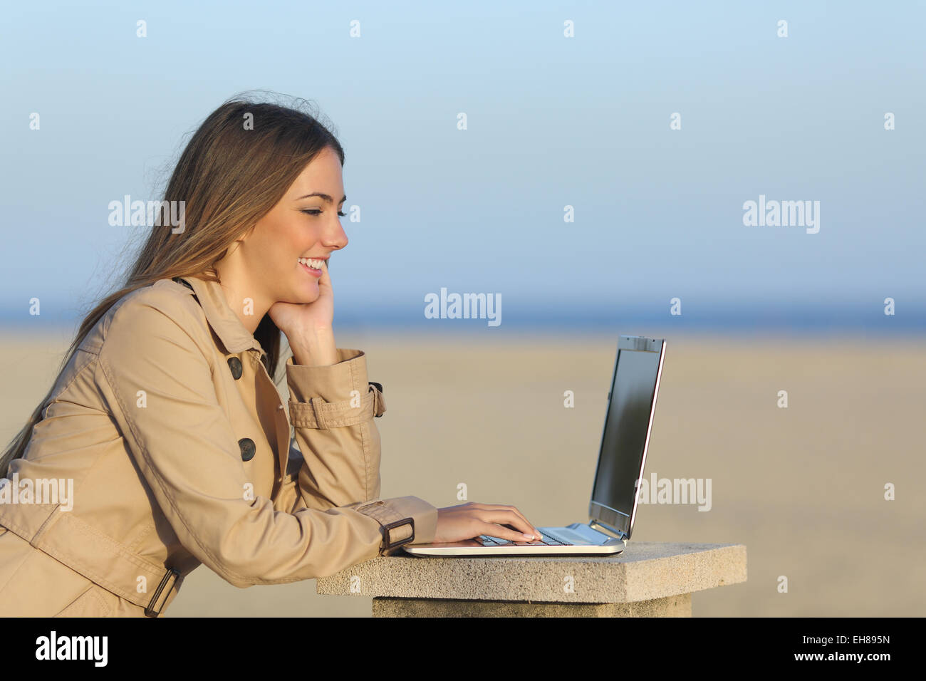 Side view of a self employed woman working with a laptop on the beach Stock Photo