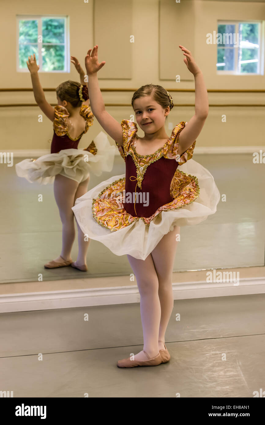 Seven year old girl in fifth position at a ballet dance dress rehearsal in a dance studio Stock Photo