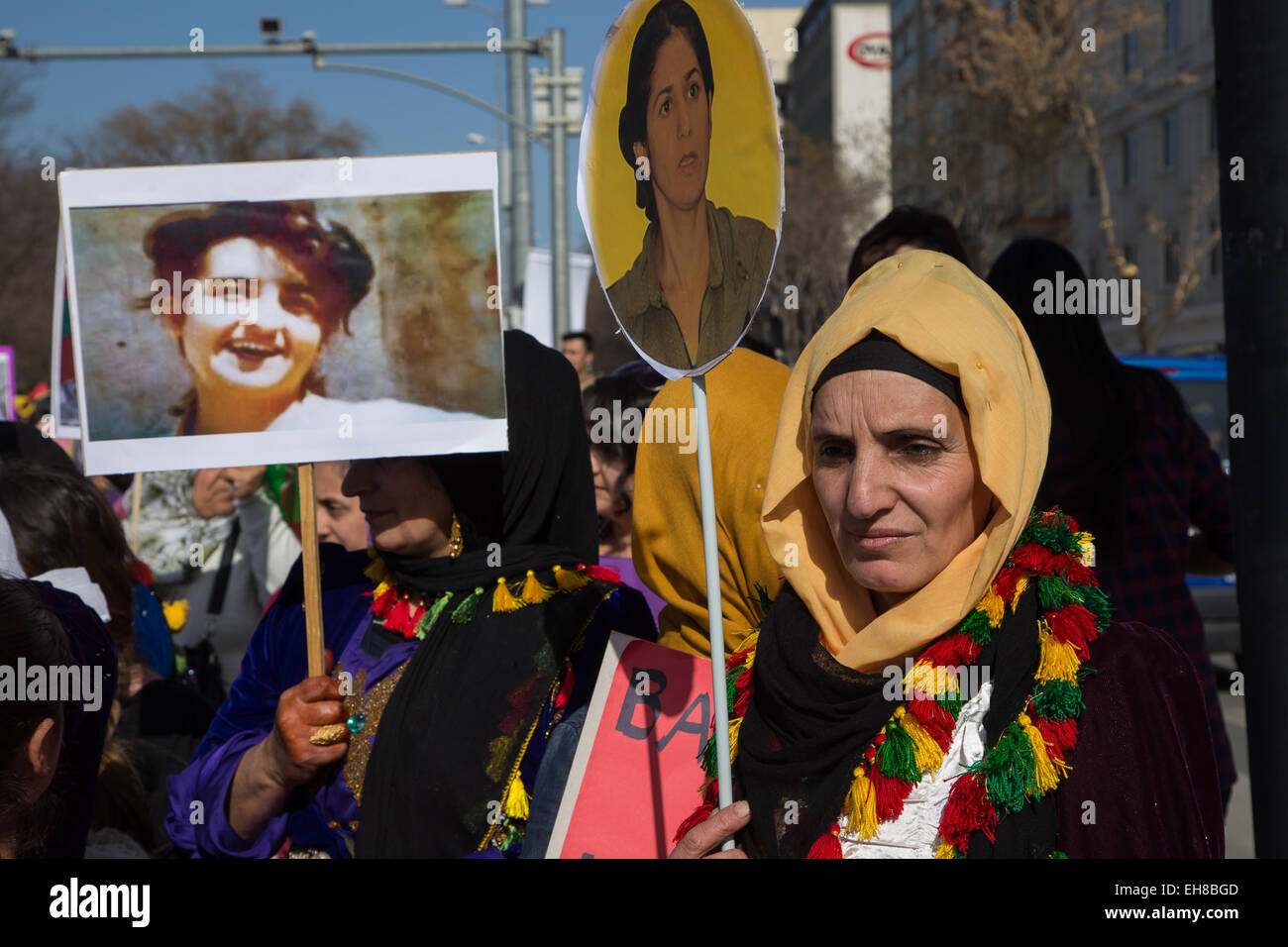 Women in traditional Kurdish costume hold a portrait of a woman ...