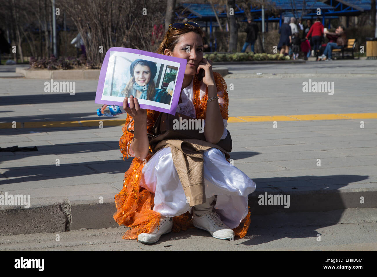 A woman in a traditional Kurdish costume holds the portrait of a ...