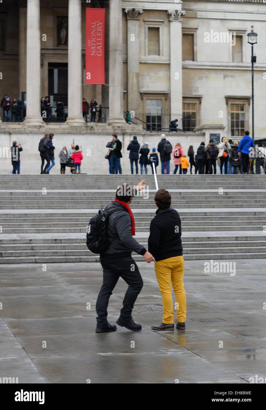 Tourists taking a selfie using an extension stick in Trafalgar Square, London. Stock Photo