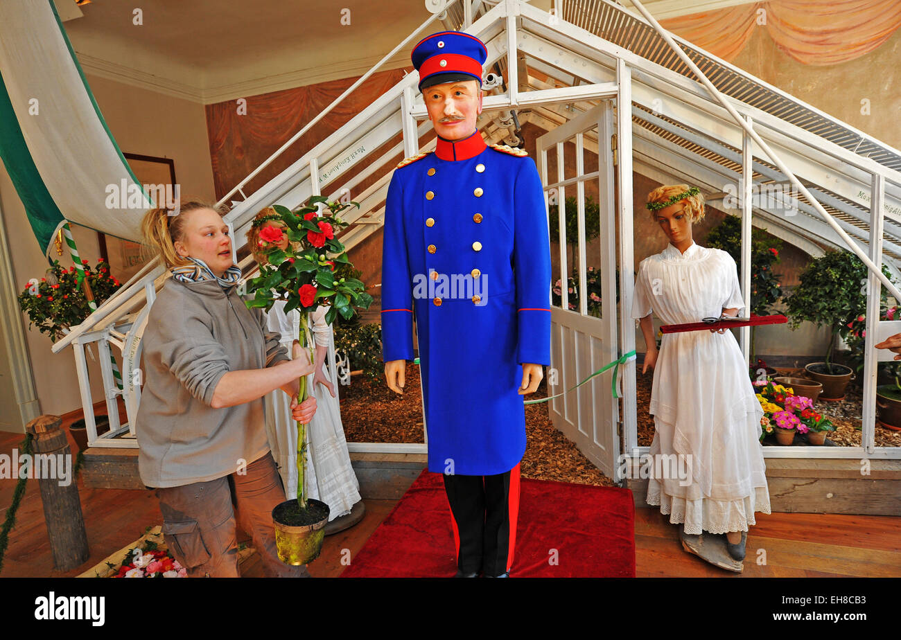 Horticulturist Sylvia Weling carries a Japanese camellia past the figurine of King Frederick Augustus III of Saxony in Zuschendorf, Germany, 09 March 2015. The 100-year-old scenery is part of the 12th German 'Japanese camellia flower show' in the Botanical Collections of the Technical University Dresden in Zuschendorf Castle. Until 06 April 2015, more than 1,000 flowers of 340 species are exhibited. 100 years ago, the Royal Court Nursery was established here. PHOTO: MATTHIAS HIEKEL/dpa Stock Photo