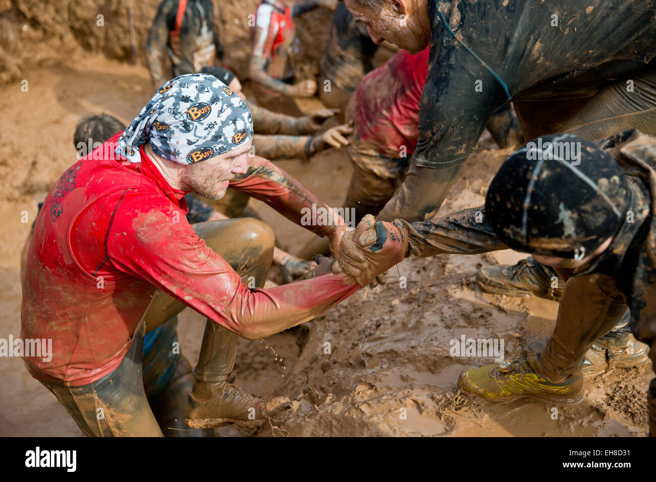 Participants help each other out of a mud pit   during the extreme course event 'Braveheart-Battle' in Muennerstadt, Germany, 7 Mrach 2015. Around 2,500 runners have to over come 28 kilometres with 50 challanging obstacles wchih includes freezing cold water, mud pits and burning fire obstacles. The Braveheart-Battle course is considered one of the toughest in Europe. Photo:  Daniel Karmann/dpa Stock Photo