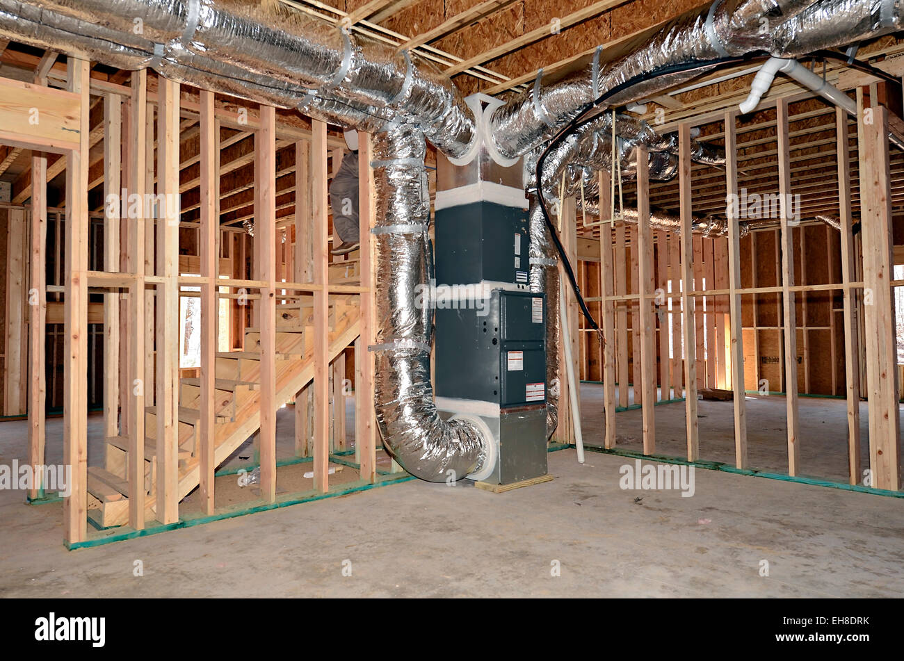 The newly framed basement area of a house. The central heat and air duct work system is beside the stairs. Stock Photo