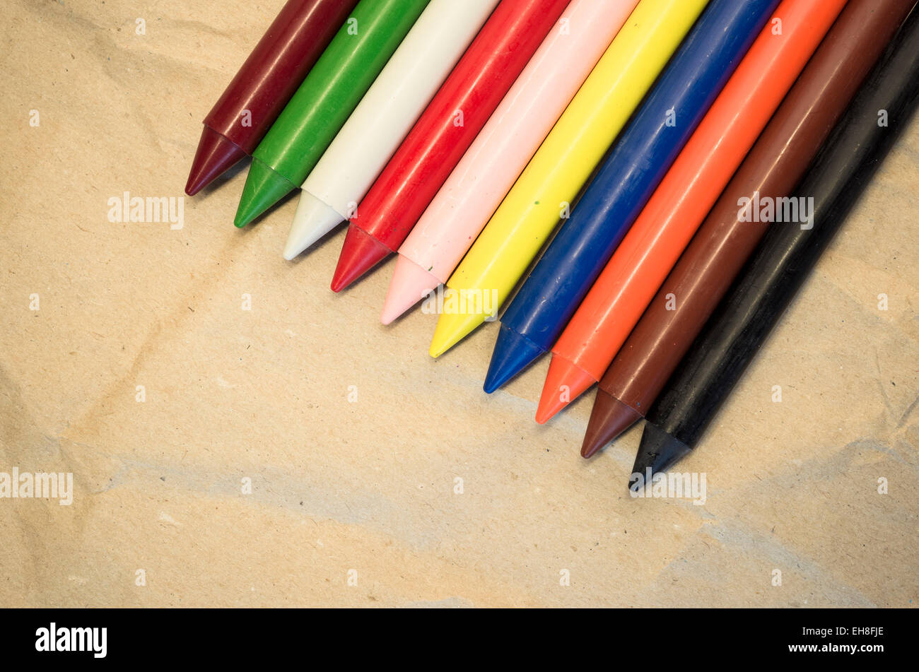 set of lined up colored wax crayons close up on a natural recycled ...