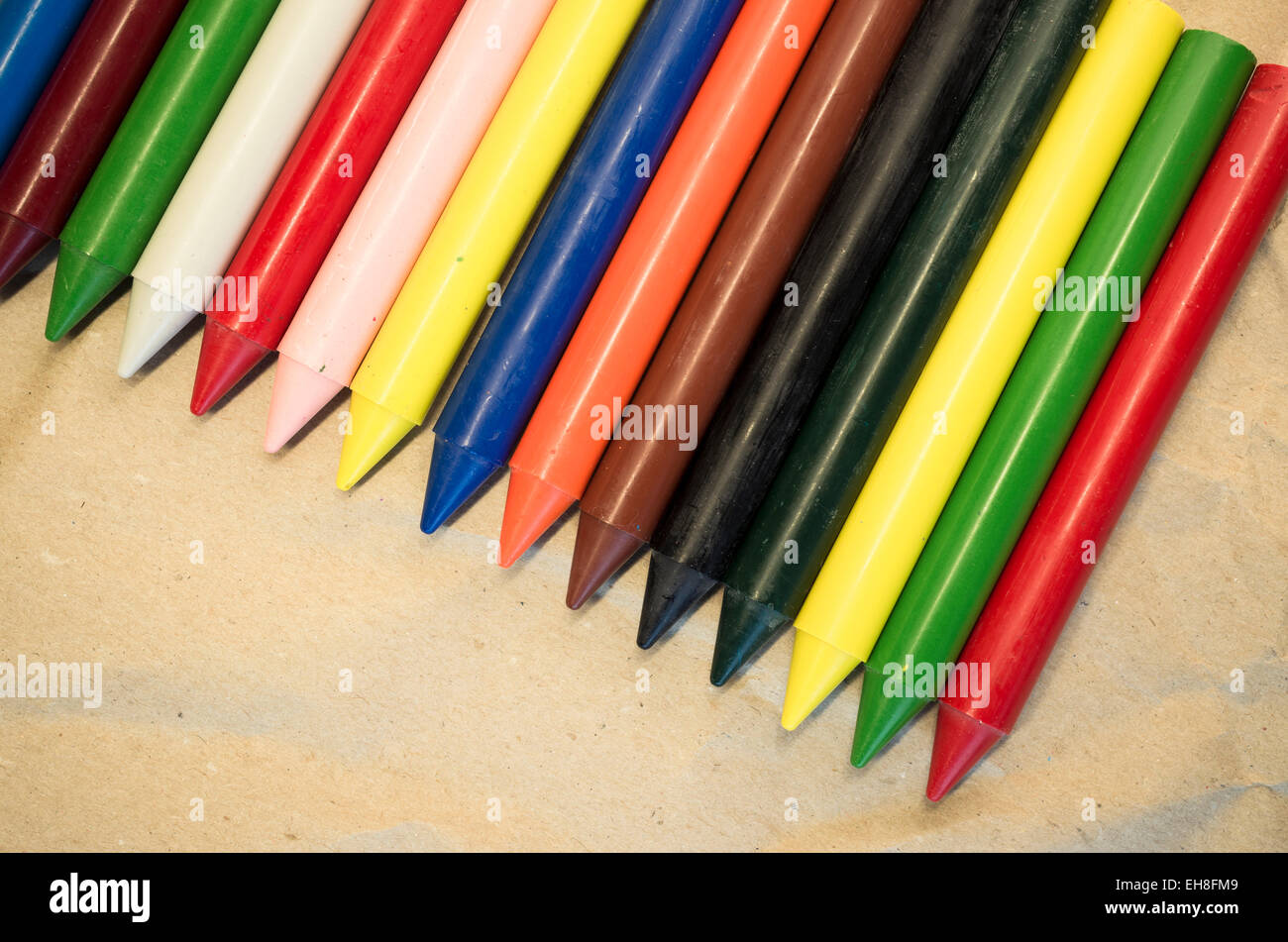 set of lined up colored wax crayons close up on a natural recycled ...
