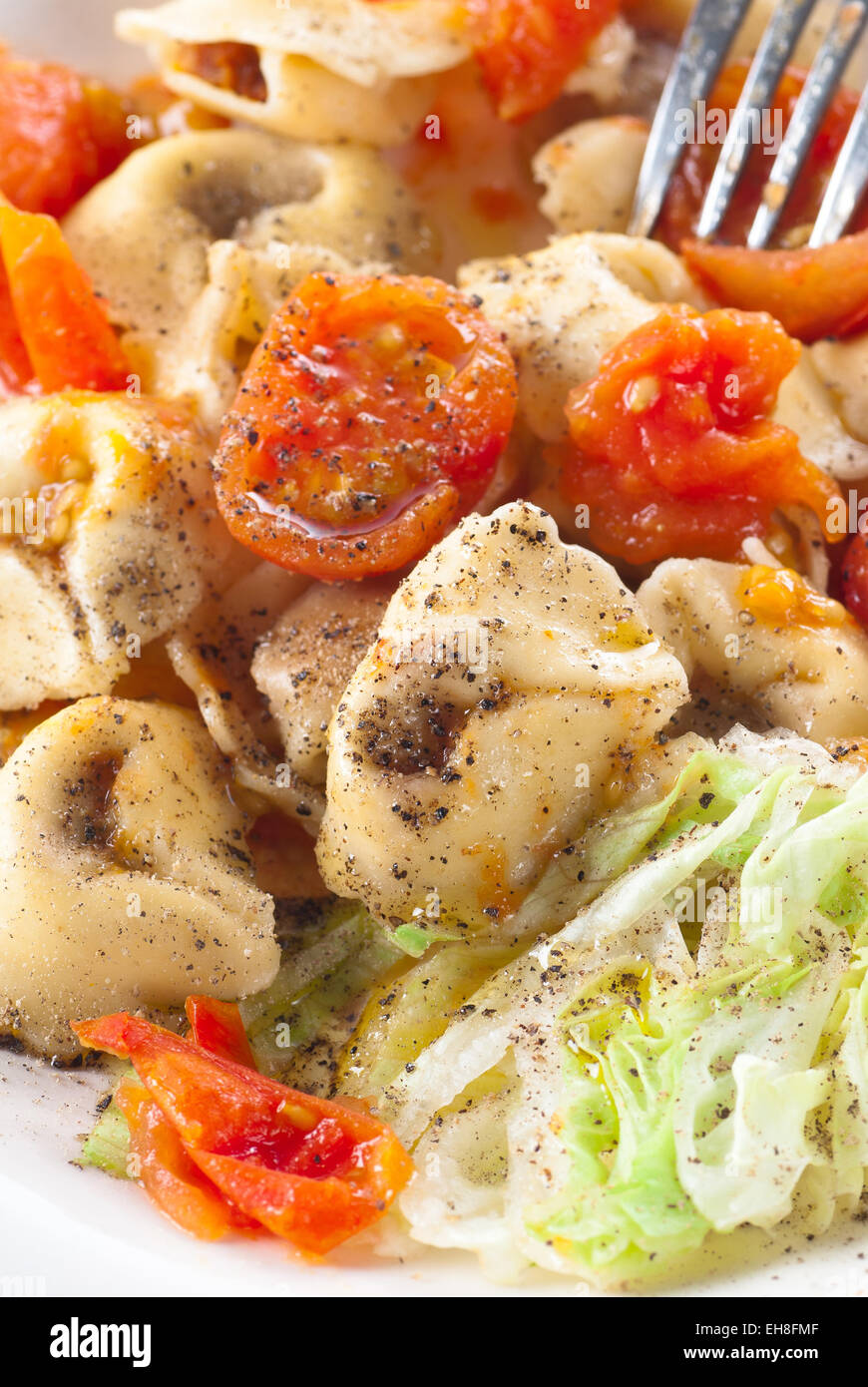 Tortellini pasta with tomatoes, olive oil and black pepper. Stock Photo